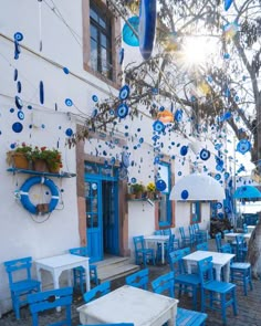 an outdoor cafe with blue chairs and tables on the side of the street in front of a white building