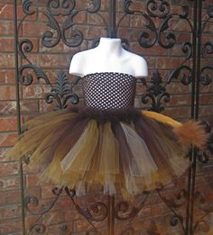 a mannequin wearing a dress made out of tulle and lace, on display in front of a brick wall