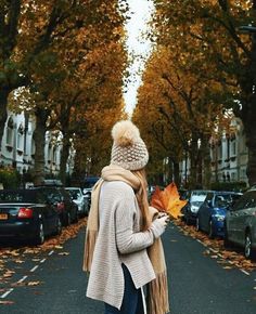 a woman is walking down the street with an autumn leaf