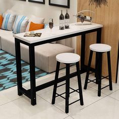 a living room with two stools next to a table and couch in front of it