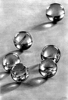 four glass balls sitting on top of a table next to each other in black and white