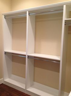 an empty walk in closet with white shelving and wood flooring on the side