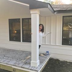 a woman standing on the front porch of a house with her hands in the air