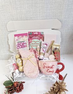 a gift box filled with coffee, candy and other holiday items on a white table