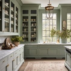 a kitchen filled with lots of green cabinets and counter top space next to a window