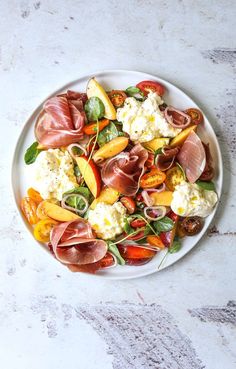 a white plate topped with meat and vegetables on top of a marble table next to a text overlay that reads quick & easy burrata salad with proscruto and nectarines