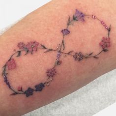 a close up of a person's arm with flowers on it and an arrow in the middle