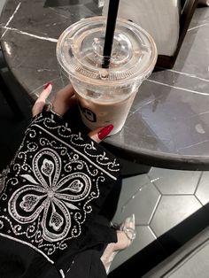 a woman is holding a drink in her hand while sitting at a table with a cell phone