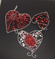 three red and white beaded fan shaped earrings on a black surface with metal wire