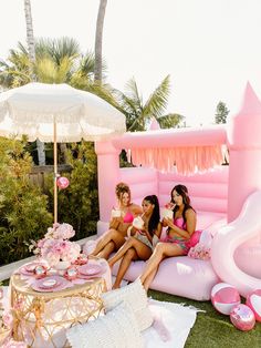 two women sitting on an inflatable pool with pink decorations and decorating items