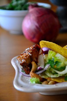 a taco with meat, lettuce and onions is on a white plate