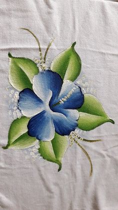 a blue flower with green leaves on a white table cloth