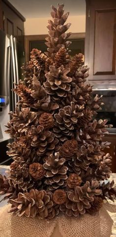 a christmas tree made out of pine cones and burlocks on a kitchen counter