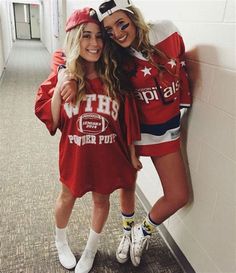 two young women are posing for the camera in their red jerseys and white socks, one is hugging the other's neck