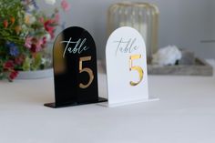 two black and white table numbers sitting next to each other on top of a table