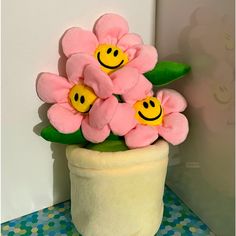 there is a potted plant with flowers and smiley faces on it, sitting next to a wall