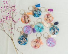 a bunch of different key chains sitting on top of a white table next to a flower