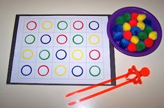 a bowl of pom - poms next to a game board and candy sticks