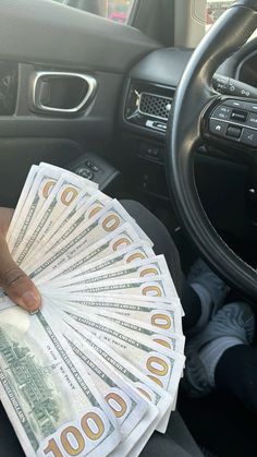 a person is holding money in their car