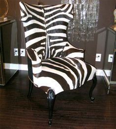 a zebra print chair sitting on top of a hard wood floor next to a chandelier