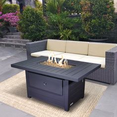 a fire pit sitting on top of a wooden table next to a couch and potted plants