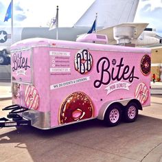 a pink ice cream truck parked in front of an airplane