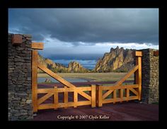 a wooden gate with mountains in the background and dark clouds above it, as seen from an overlook