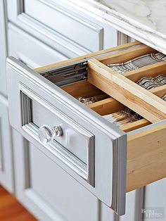 an open drawer in a white kitchen with marble counter tops