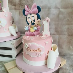 there is a pink cake with a minnie mouse on it and other decorations around it