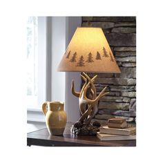 a lamp that is sitting on top of a table next to a vase and book