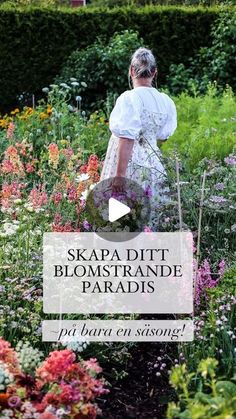 a woman walking through a garden filled with flowers