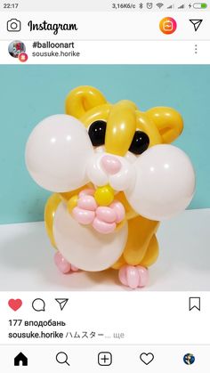 a small yellow and white balloon shaped like a hamster holding an egg in it's mouth