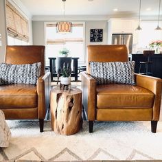 two brown leather chairs sitting next to each other in a living room