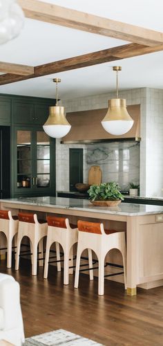 a kitchen with wooden flooring and white chairs in front of an island counter top