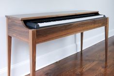 a wooden piano sitting on top of a hard wood floor next to a white wall