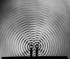 two people are standing in front of a circular pattern on the wall with their hands together