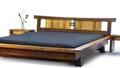 a wooden bed frame with two night stands and a vase filled with flowers on the side