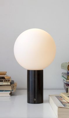 a white light sitting on top of a table next to books and a pile of books