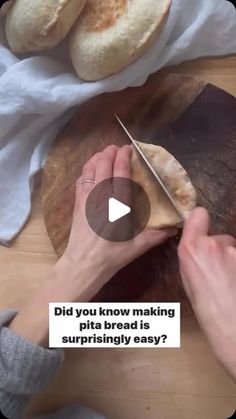 a person cutting bread on top of a wooden table