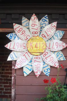 a large sunflower made out of license plates on the side of a garage door