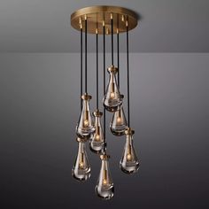 a chandelier hanging from the ceiling with five clear glass drops and gold accents