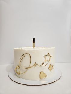 a white cake with gold stars on it and one candle in the shape of hearts