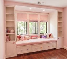 a window seat in the corner of a room with built - in bookshelves