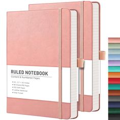 a pink notebook is shown next to a stack of colored papers