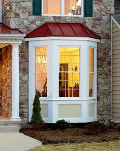 a house that has a red roof and white trim on the side of it with windows