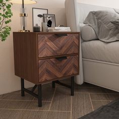 a nightstand with two drawers next to a bed and a potted plant on the side