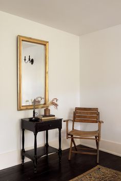 a wooden chair sitting next to a table with a mirror on it