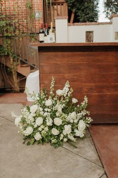 a bouquet of white flowers sitting on the ground in front of a wooden box and stairs