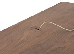 a wooden table with a white cord connected to the top and bottom of it, on which is a hole in the wood