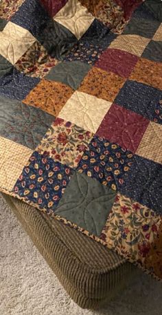 a bed that has a quilt on it and is made with many different colored squares